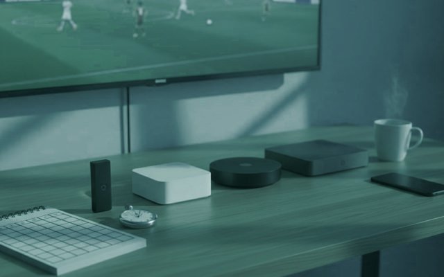 Five streaming devices, a notebook scoring grid and a stopwatch in front of a TV showing a football match